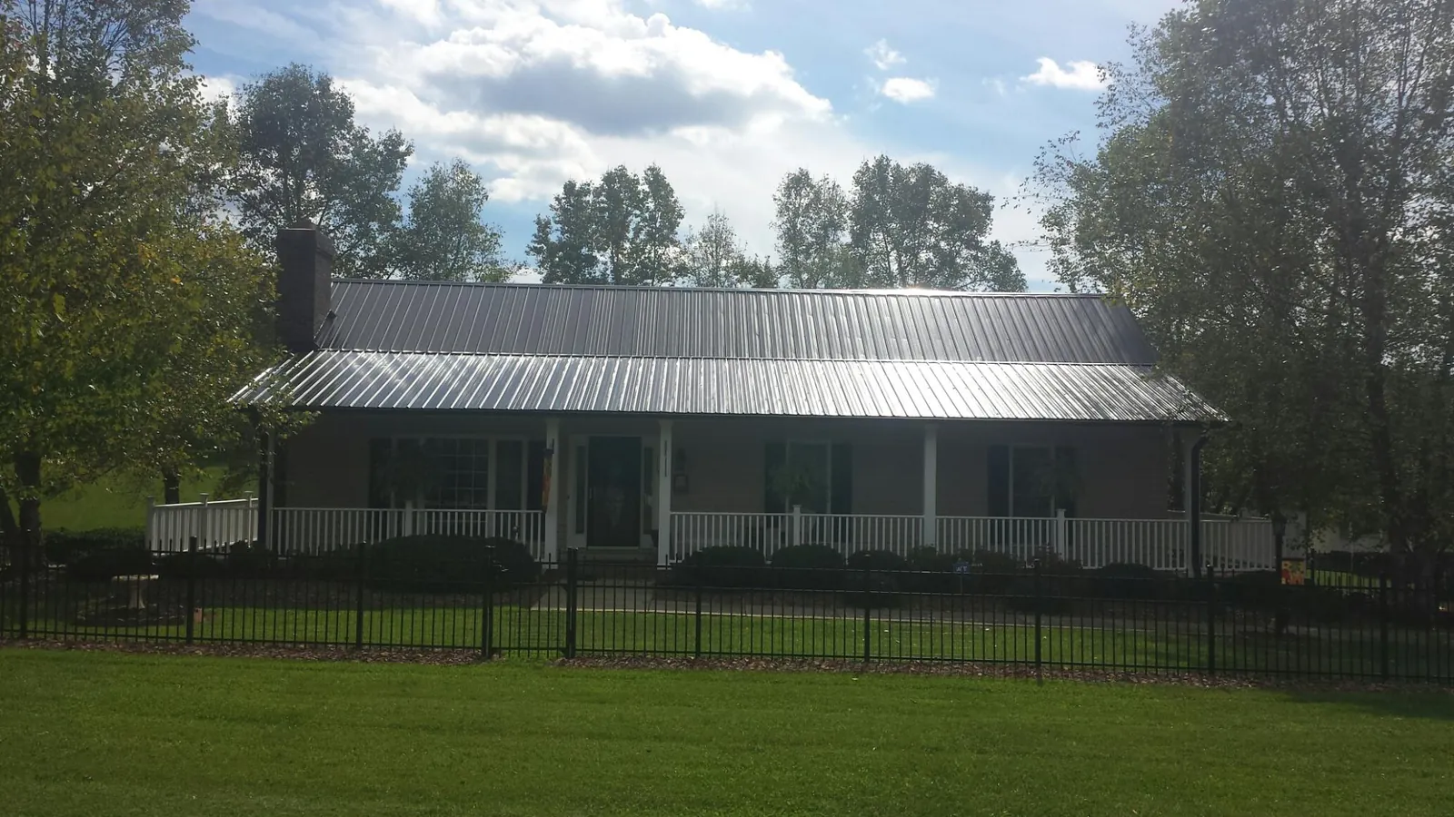 Gray metal roof on a brick ranch with a full width front porch — Gutter Guard Installation work by our crew in Stromsburg