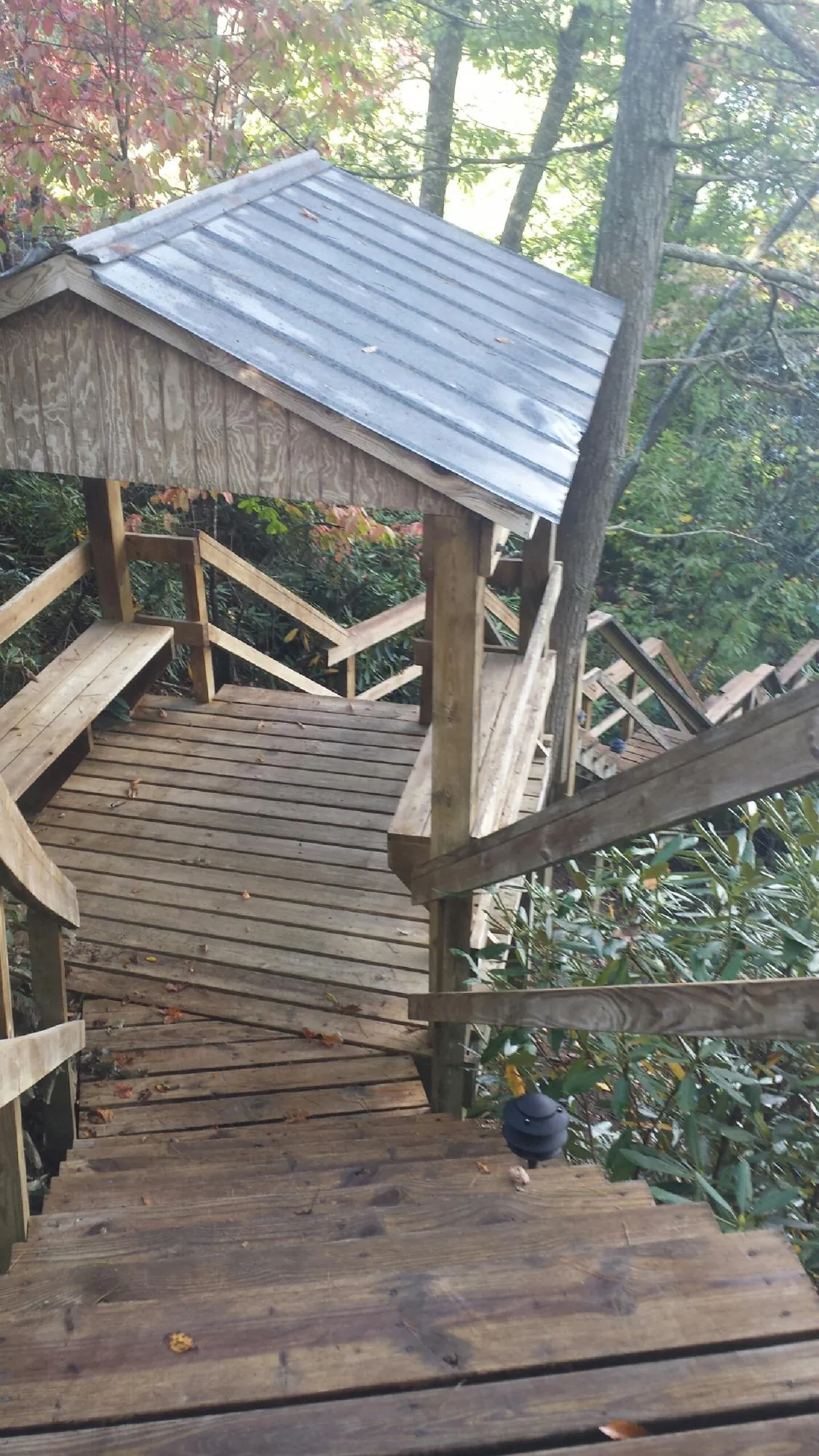 Metal roofed shelter over wooden steps on a wooded walkway — Skylight Repair & Installation work by our crew in Stromsburg