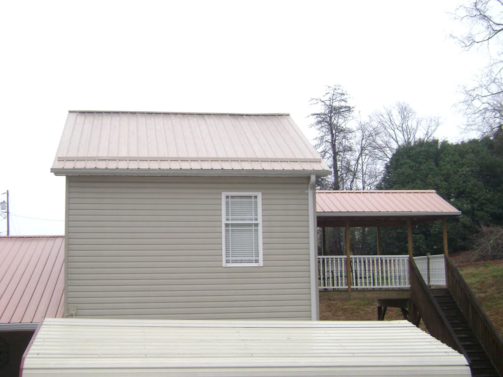 Tan metal roofs on a two story addition and attached porch, from a Roof Replacement job in Stromsburg