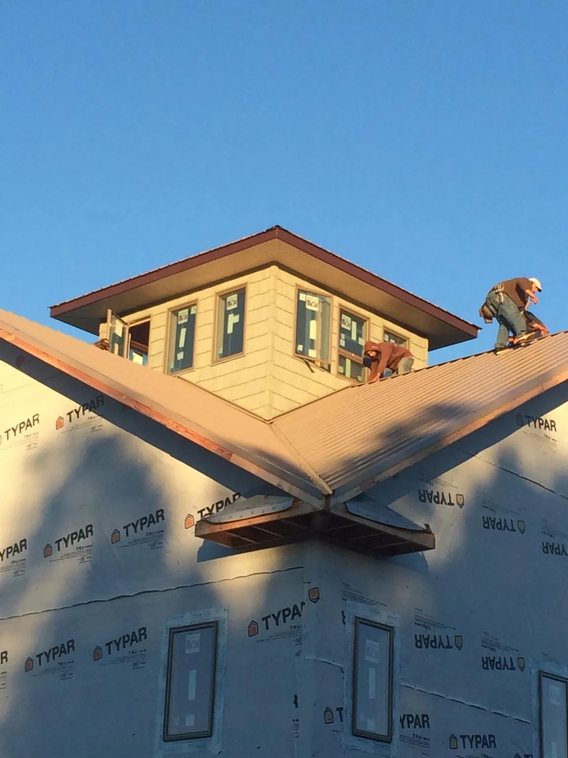 Roofers working around a rooftop cupola on a new metal roof at sunset — Roof Waterproofing in Stromsburg by Roofing Brothers